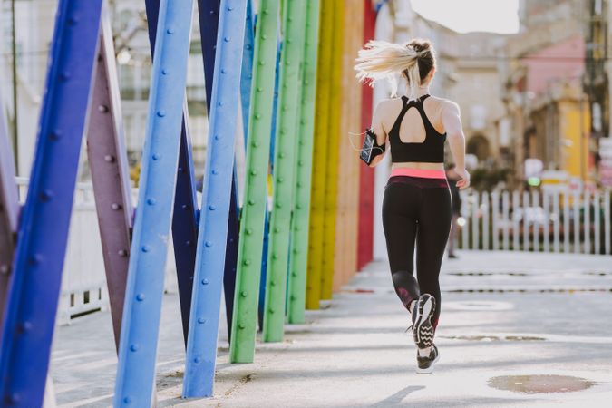 Woman with earphones running on street