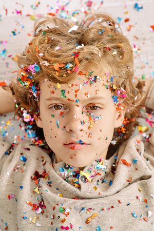 Fair haired kid with confetti on face and clothes
