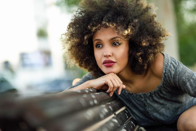 Female deep in thought in casual dress sitting on park bench