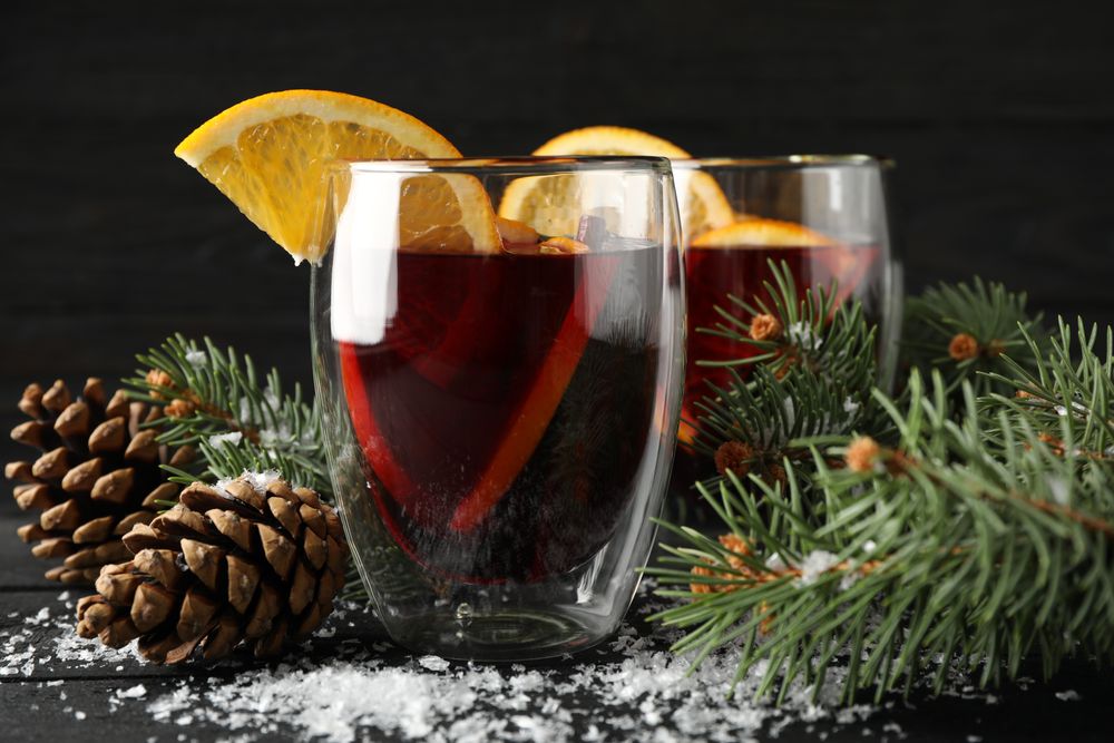 Glasses of tasty mulled with orange on decorated background, space for text