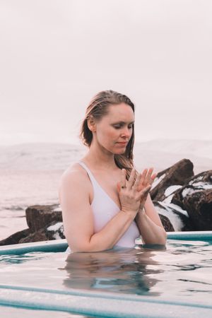 Woman sitting in pool near stones