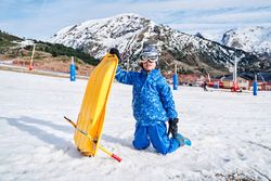 Kid with sleigh against snowy mountains