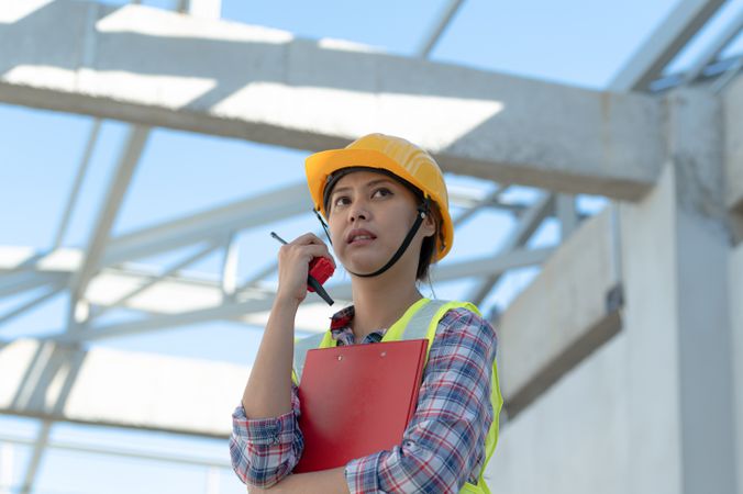 Female engineer with radio commander on construction site.