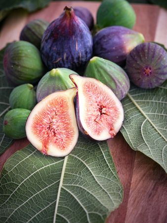 Whole and halved figs on wooden surface