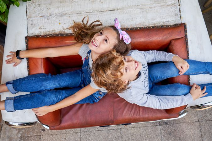 Cheerful children relaxing on vintage sofa on street
