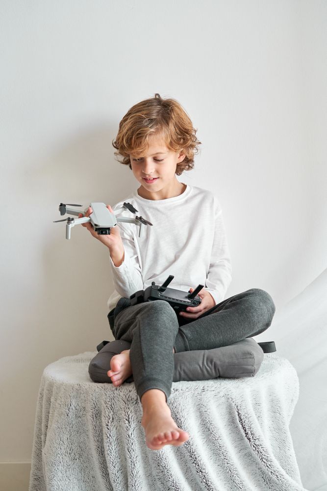 Content child sitting on table and looking at toy drone