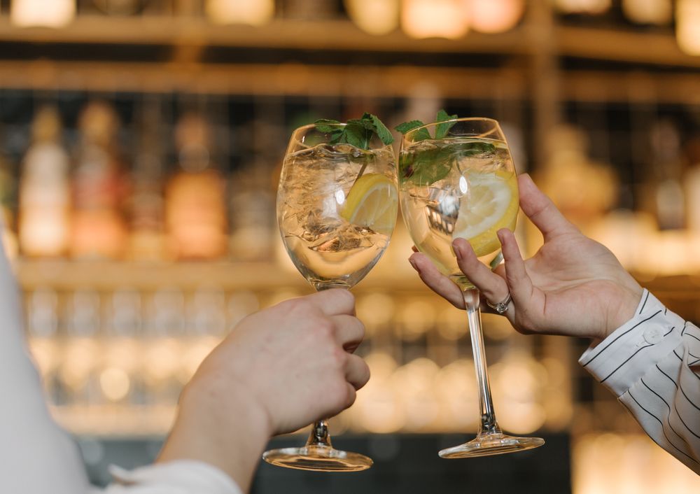 Close-up view of women hands toasting with cocktails in bar