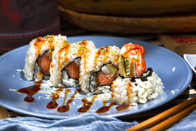 Tasty sushi poured with sauce on blue plate