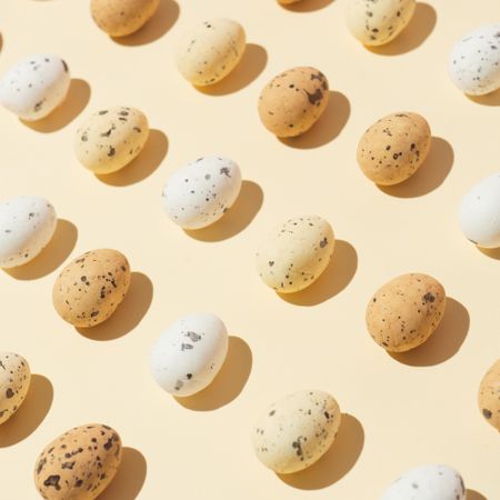 Speckled eggs  in rows on pastel yellow background