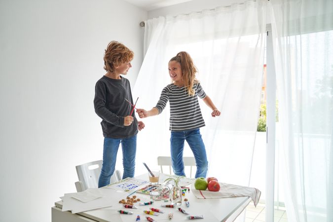 Girl and boy fighting using paintbrushes