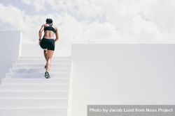 Rear view of a female athlete running up stairs of a building 42gwKb