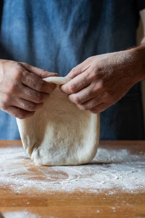 Crop man flattening dough for pizza