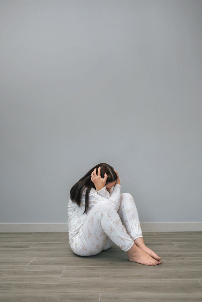Unrecognizable woman in grey room clutching head