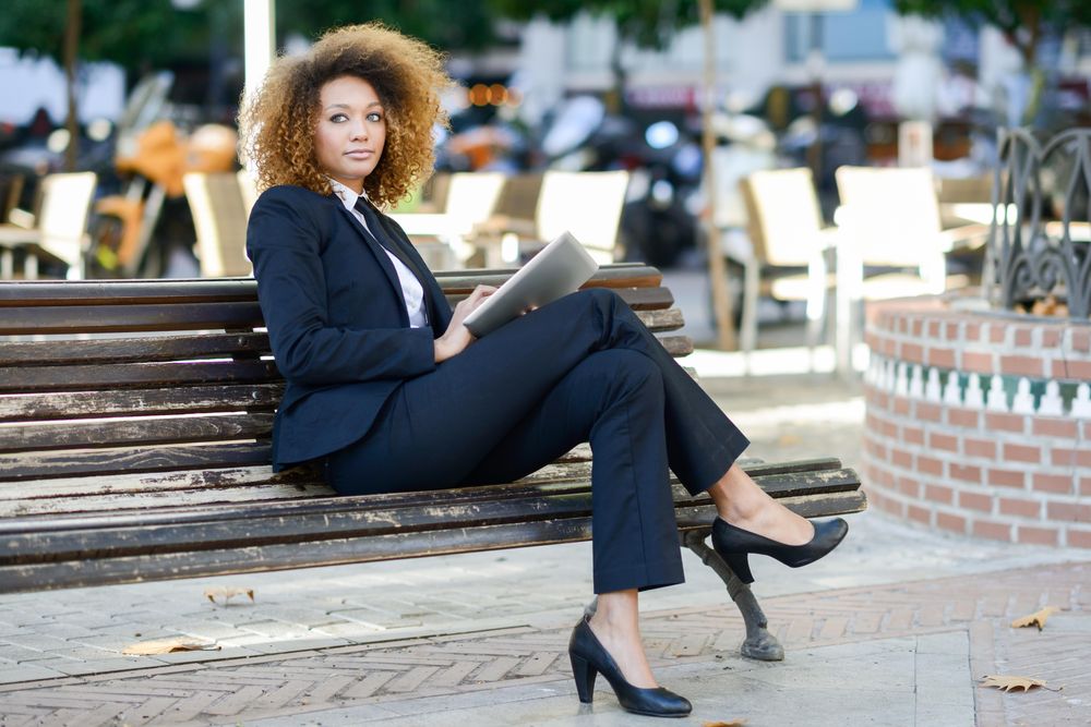 Serious woman in suit up from her digital tablet on outdoor bench