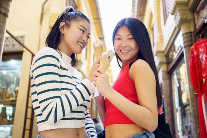 Two women standing outside with ice cream cones and smiling