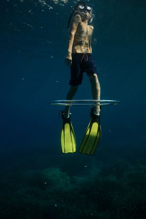 Faceless boy swimming through bubble air ring