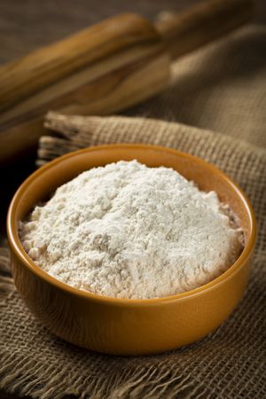 Bowl with wheat flour on the table.