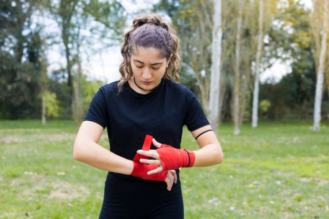 Boxer woman wrapping hands bandage for boxing outdoors