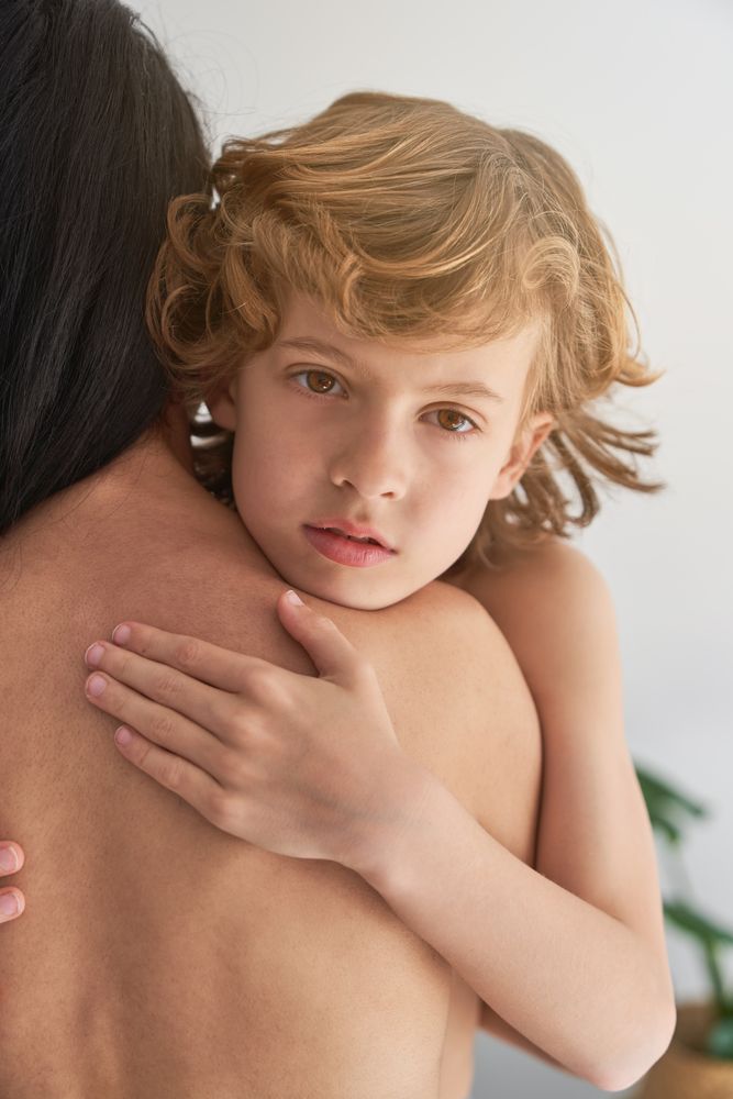 Boy embracing faceless topless mother