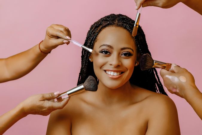 Happy Black woman with hands doing her make up