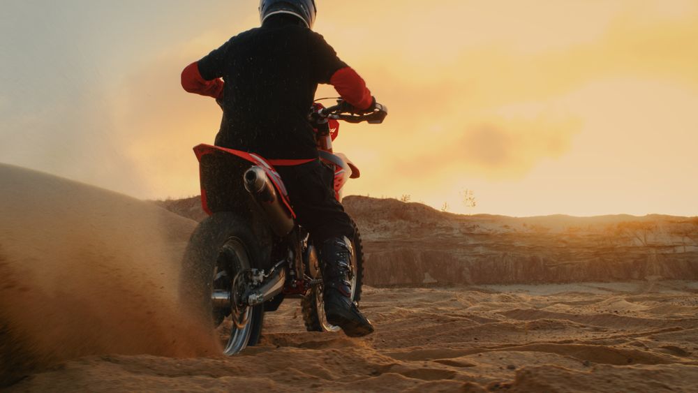 Professional Bike Rider Blasts-off on His FMX Motorcycle Over Sandy Off-Road Track.