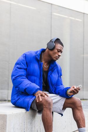 Black man with headphones on smartphone in city