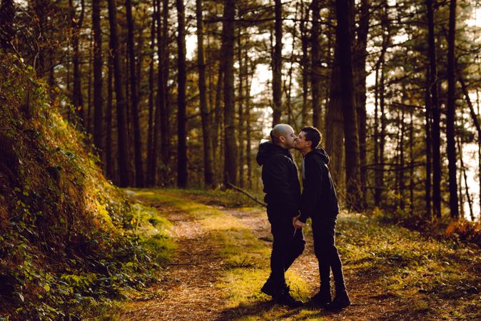 Men hugging and kissing on countryside road near dog