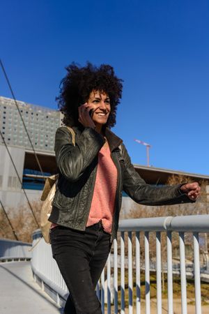 Woman with afro hair looking at her phone while walking.