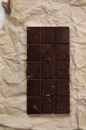 Chocolate bar with nuts on craft paper, top view