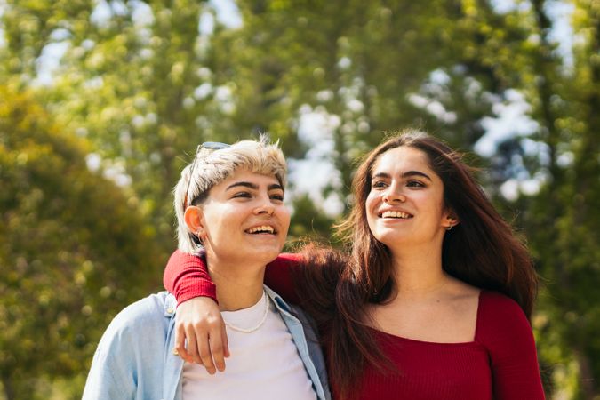two young women walking and smiling in a park