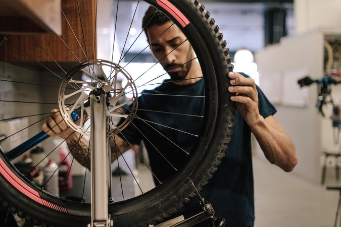 Man working on a bicycle wheel in a repair shop