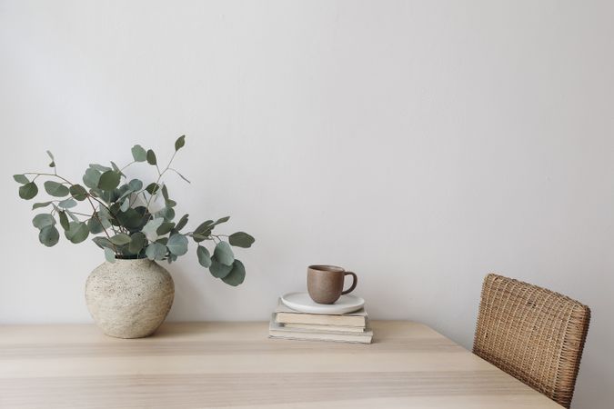 Wooden table with wicker chair, books and vase