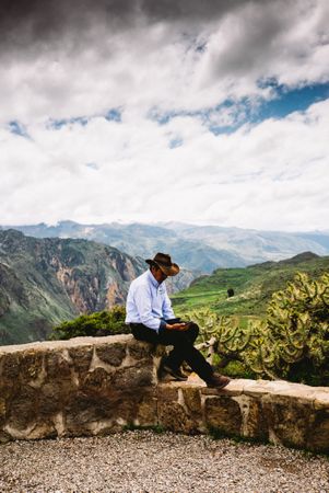 Side view of man checking phone in front of scenic view in Andes