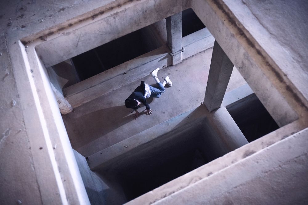 Young man performing breakdance element in unfinished building