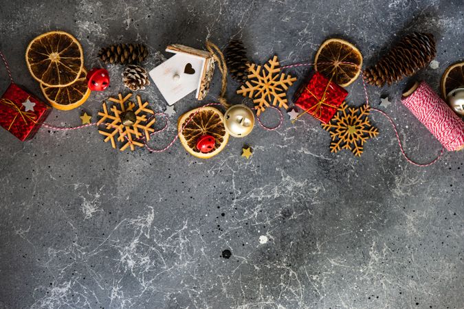 Top view of wooden snowflakes, dried orange slices and pine cones on marble table