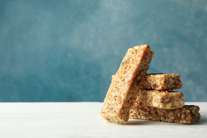 Tasty granola bars on wooden table against blue background