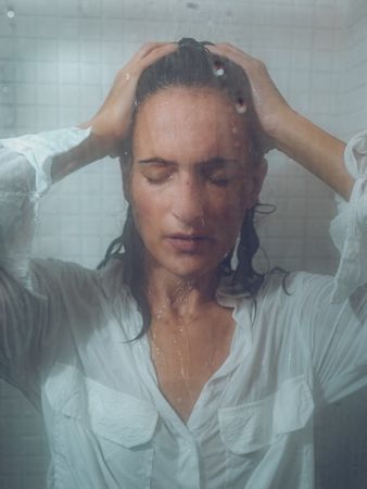 Seductive female in wet shirt in shower cabin