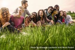 Multi-ethnic group of friends sitting together in the grass 0WOPk1