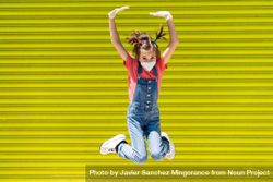 Cute girl jumping in protective mask against a yellow wall 5RmDD0