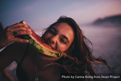 Young woman eating a watermelon slice at the beach 65XXk5