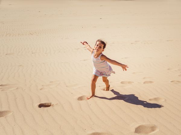 Cute little girl playing with sand at beach