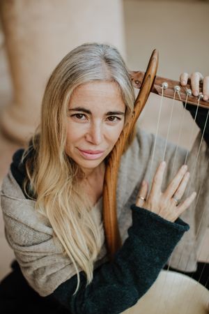 Romantic female musician playing lyre in terrace