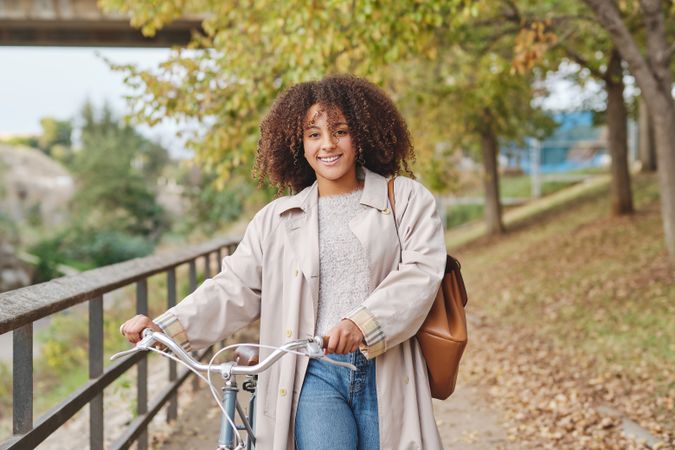 Positive Black Latina woman with bicycle in autumn day