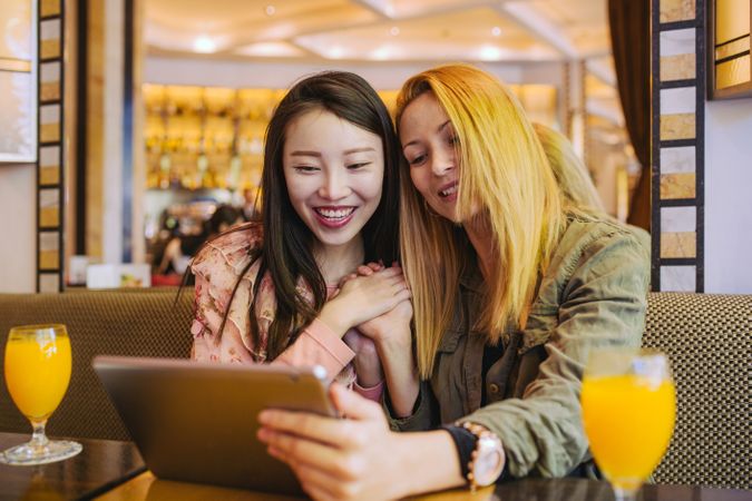 Female friends using tablet in cafe