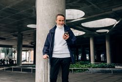 Stylish mature tourist checking phone outdoors