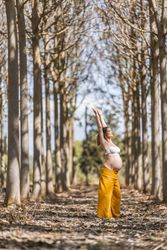 Concentrated adult expectant mother practicing yoga in park