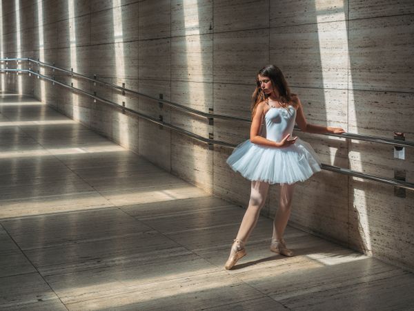 Ballerina doing ballet posing at rail in classroom