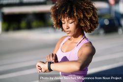 Female with afro hair looking at her smart watch during workout 4B6gx4