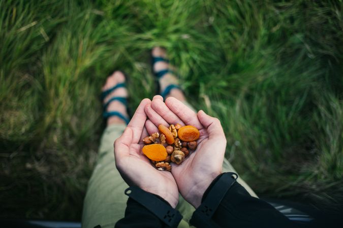 Hands holding trail mix of apricot and nuts
