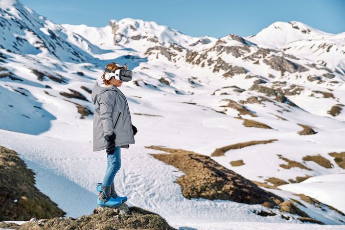Anonymous boy in VR goggles on snowy mountain slope